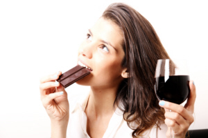 Portrait of a beautiful, latin Woman drinking red wine and eating chocolate.